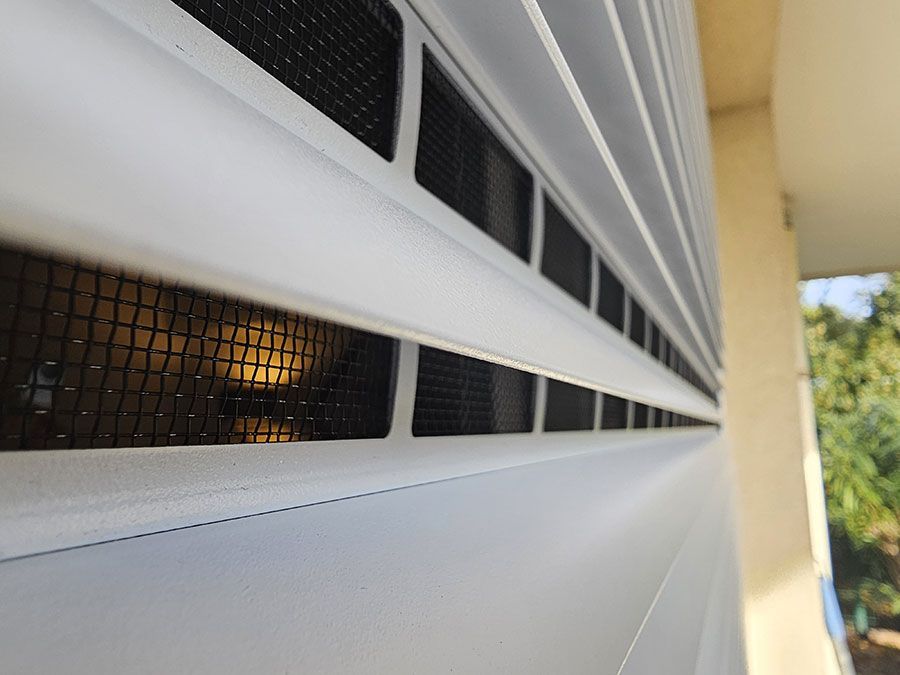 Unité de climatisation blanche avec grilles d'aération noires, extérieure.