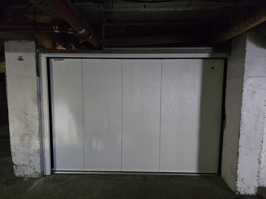 Porte coulissante blanche isolée au sous-sol, entre des colonnes en béton.