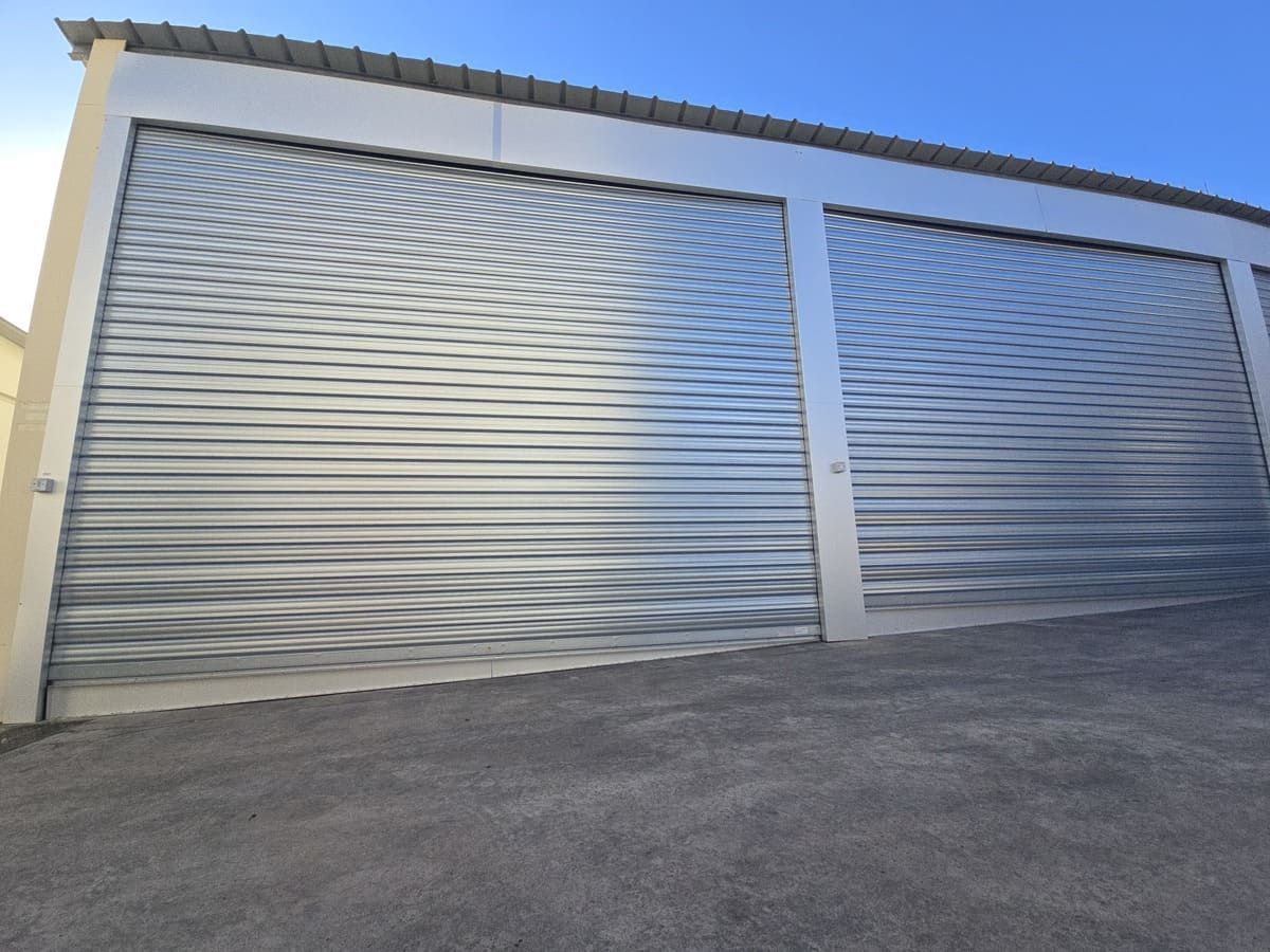 Portes sectionnelles métalliques d'un entrepôt de stockage, sur fond de ciel bleu dégagé.