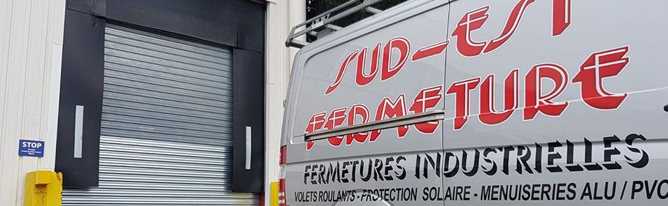 Camionnette arborant le logo de l'entreprise, stationnée près d'un quai de chargement d'entrepôt.