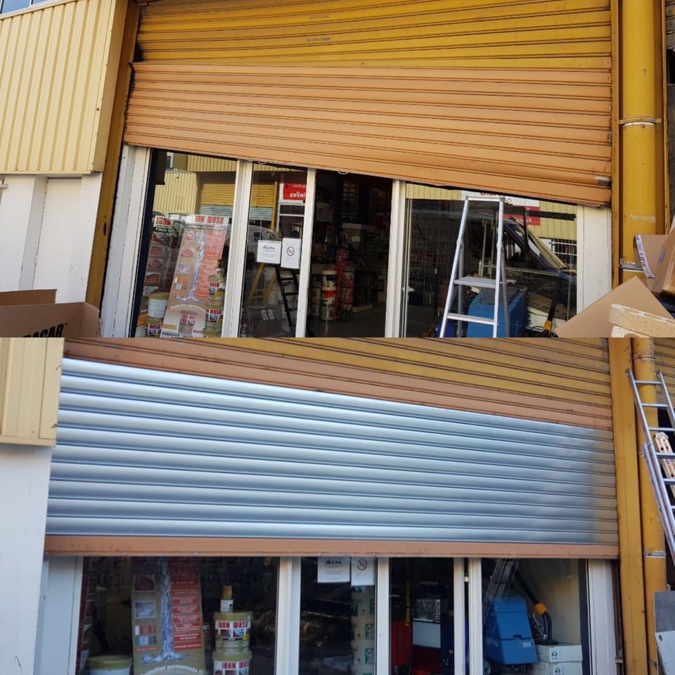 Façade de magasin avec un rideau métallique partiellement ouvert, exposant la marchandise à travers des vitrines.