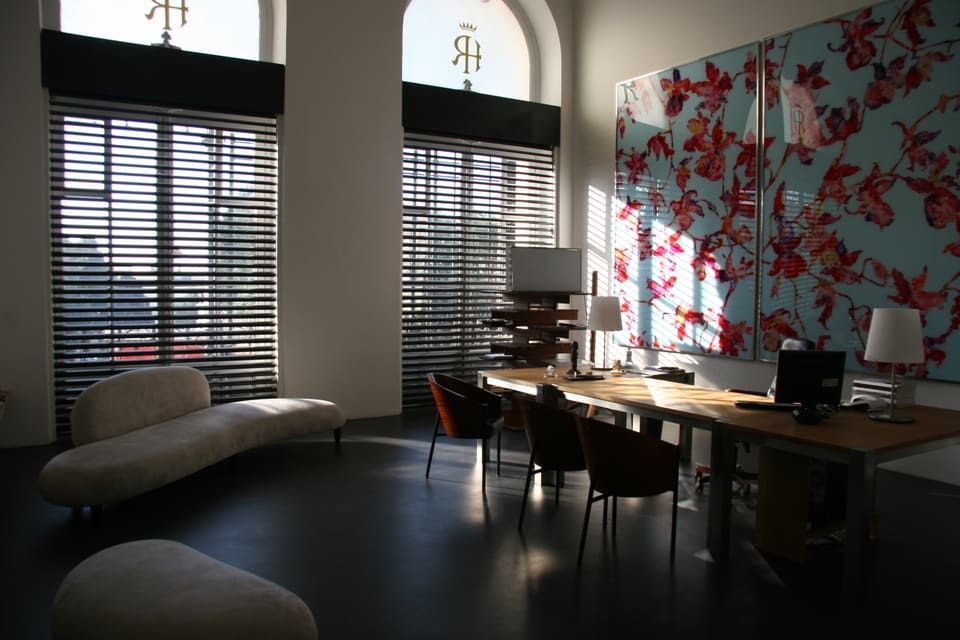 Bureau lumineux avec de grandes fenêtres, sols foncés, mobilier moderne et œuvres d'art florales.