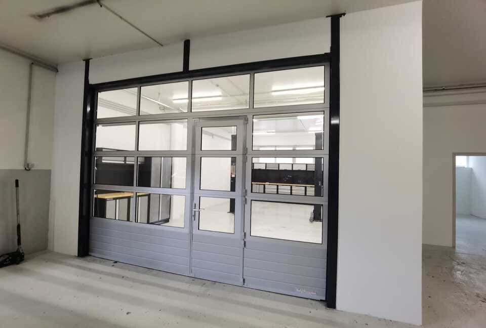 Porte commerciale en verre et métal à carreaux quadrillés, montée sur un mur blanc.