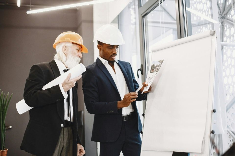 Zwei Baufachleute prüfen Baupläne und einen Entwurfsplan.