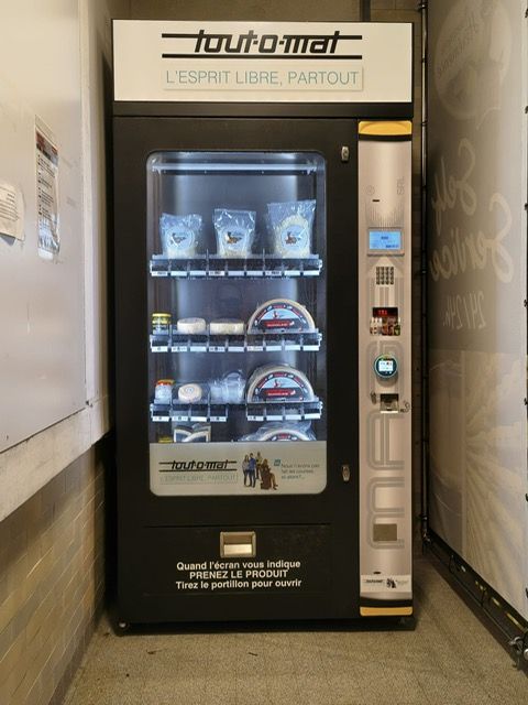 Personne derrière une table présentant des échantillons de fromages, certains emballés, d'autres non.