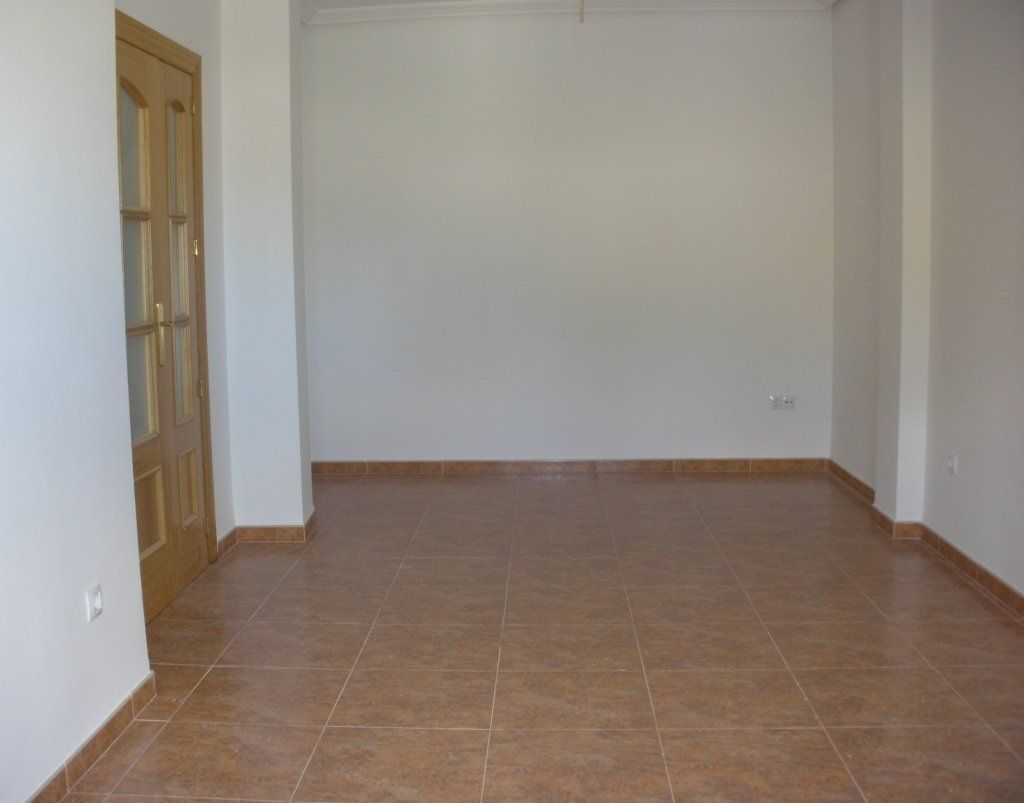 Una habitación vacía con suelo de baldosas y paredes blancas.