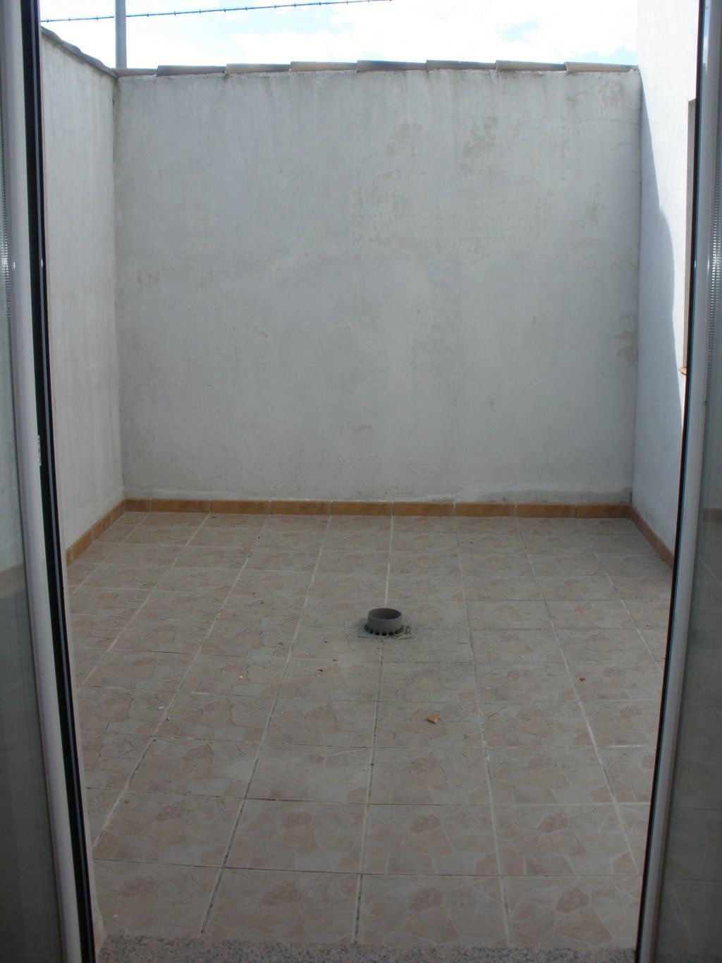 Una habitación vacía con suelo de baldosas y una pared blanca.