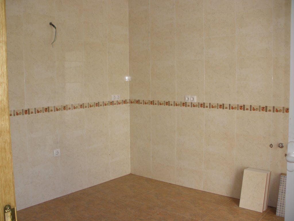 Una cocina con azulejos blancos y una puerta de madera.