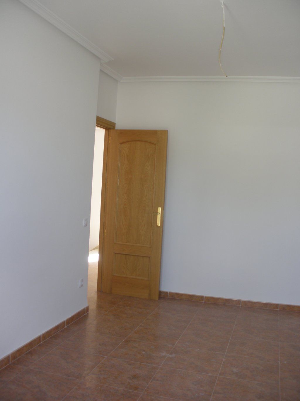 Una habitación vacía con una puerta de madera y paredes blancas.