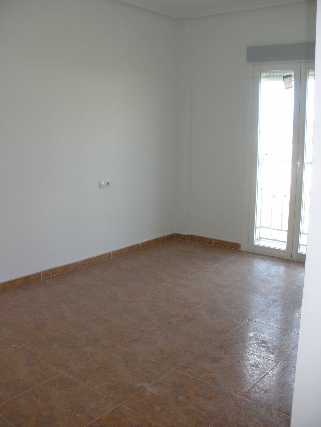 Una habitación vacía con suelo de baldosas y paredes blancas.