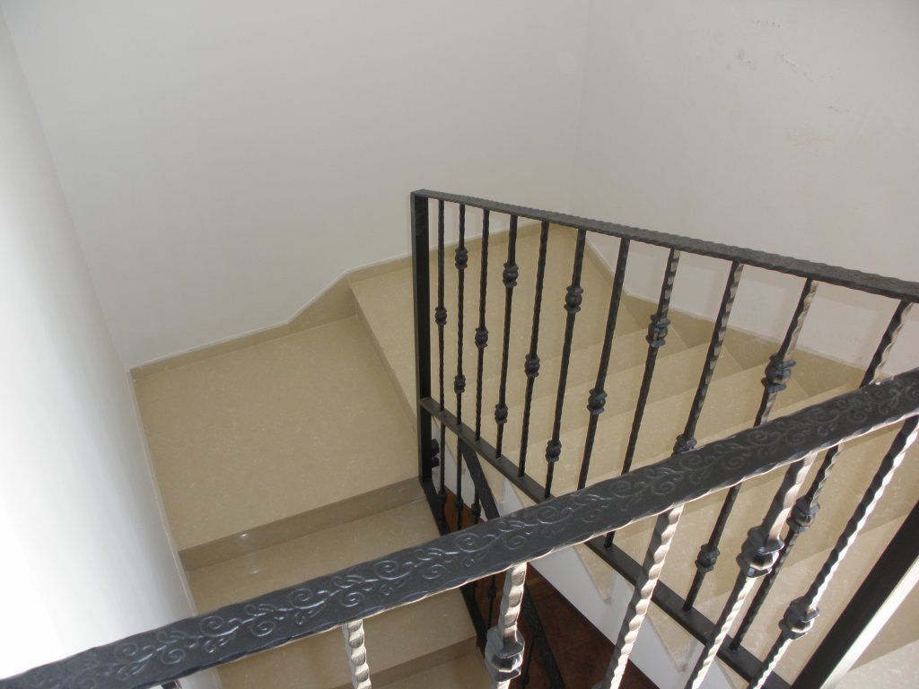 Una escalera con barandilla de hierro forjado que conduce al segundo piso.