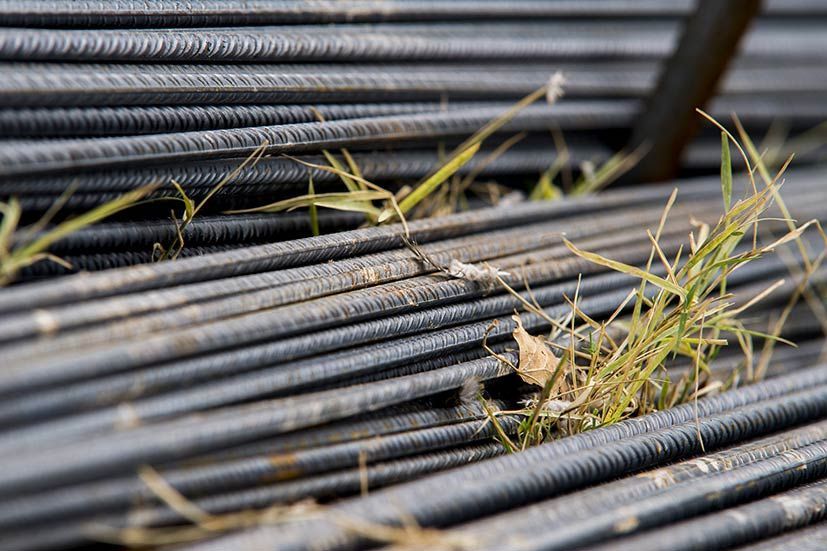 Un primer plano de una pila de barras de acero con hierba creciendo dentro de ellas.