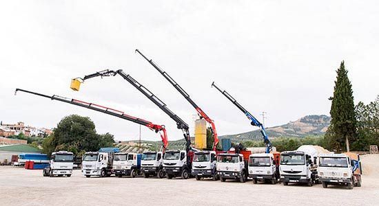 Una fila de camiones y grúas están estacionados en un estacionamiento.