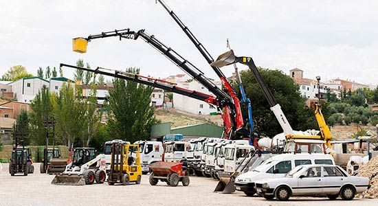 Muchos vehículos de construcción están estacionados en un estacionamiento.