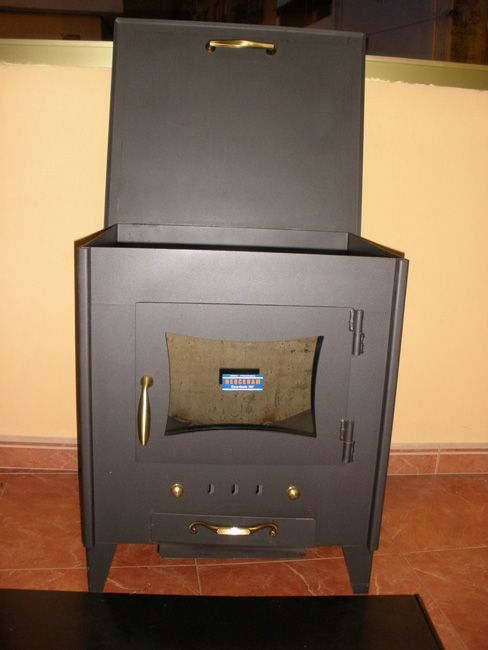 Una estufa negra con la puerta abierta está colocada sobre un suelo de baldosas.