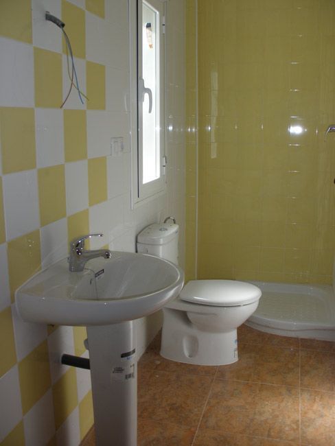 Un baño con azulejos amarillos y un lavabo e inodoro.
