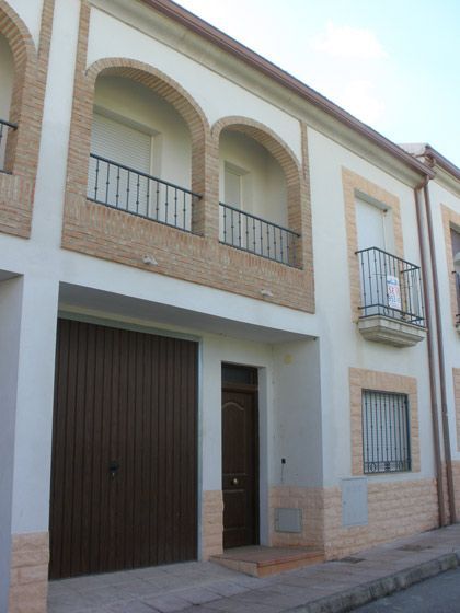 Un edificio blanco con una puerta de garaje marrón y balcones.