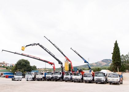 Una fila de camiones con grúas estacionados en un estacionamiento.