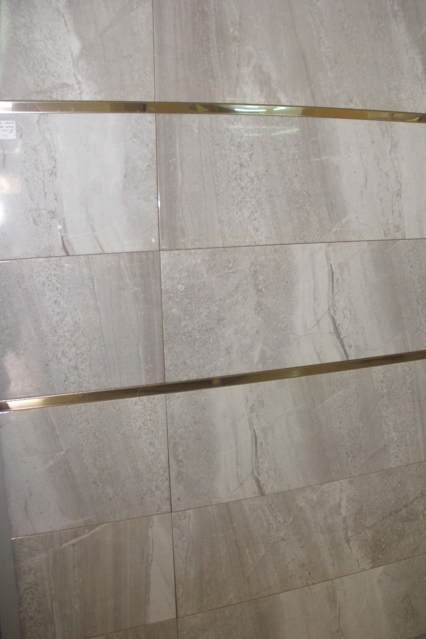 Un primer plano de una pared de azulejos con un borde dorado.