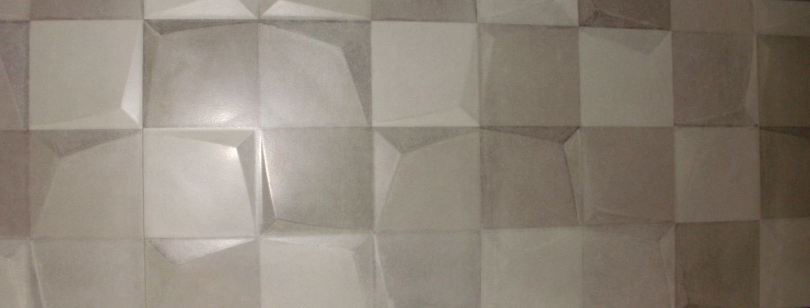 Un primer plano de una pared de azulejos grises con un patrón geométrico.
