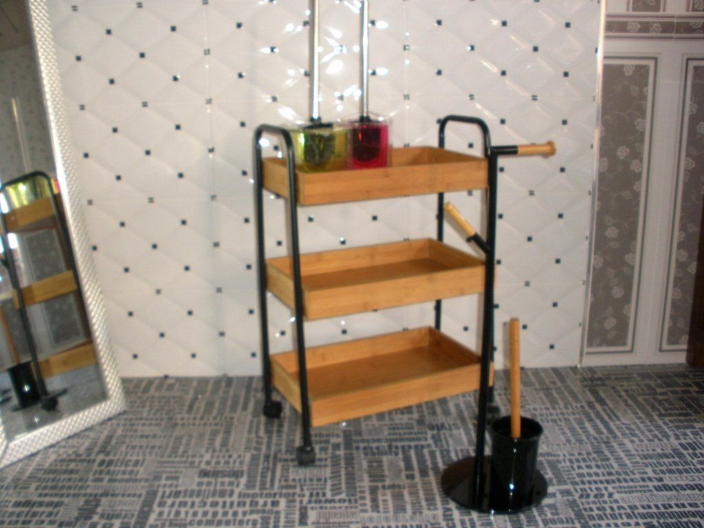 Un carrito de baño con tres estantes y un cepillo de baño.