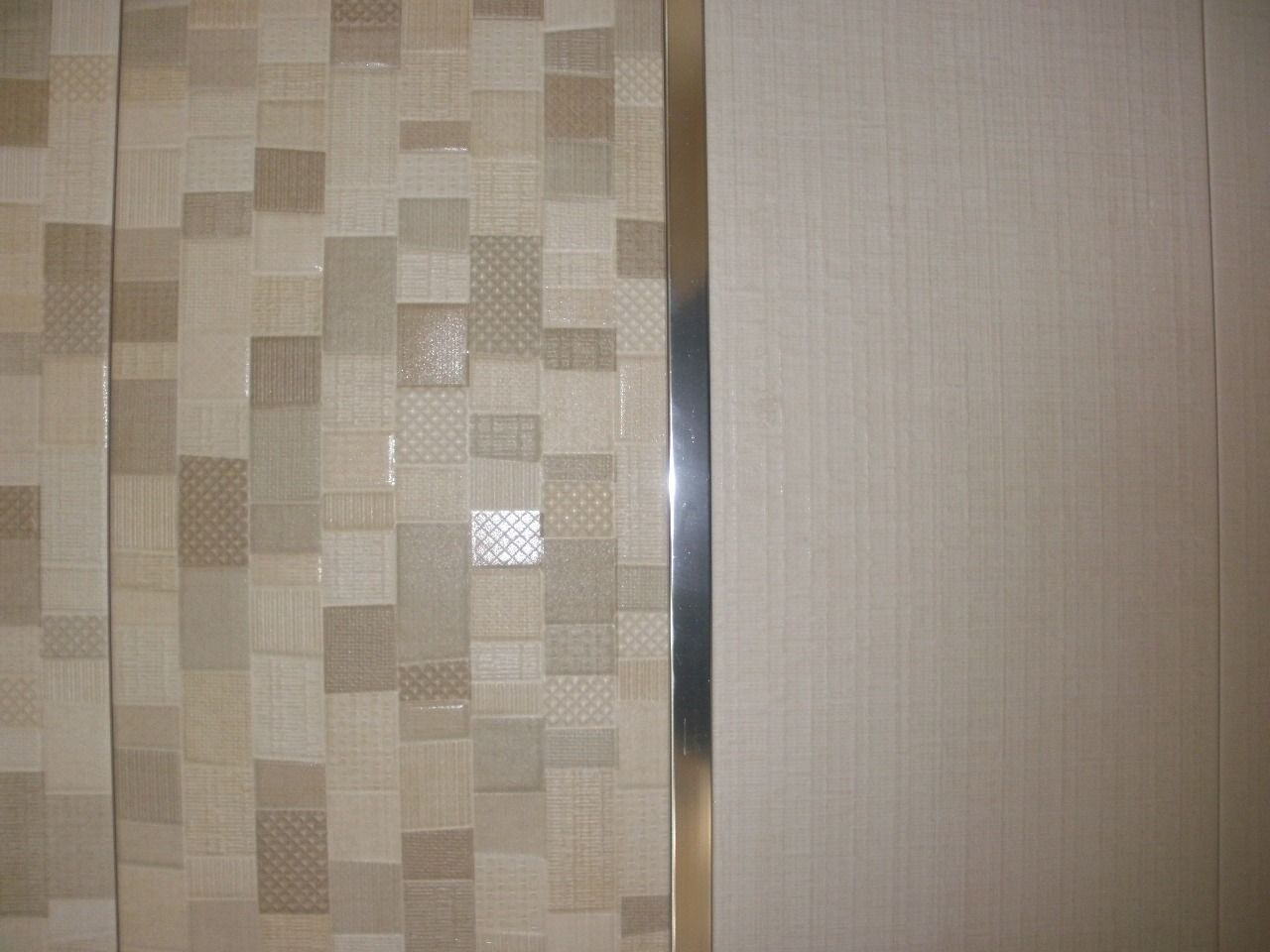 Un primer plano de una pared de azulejos con moldura de metal.