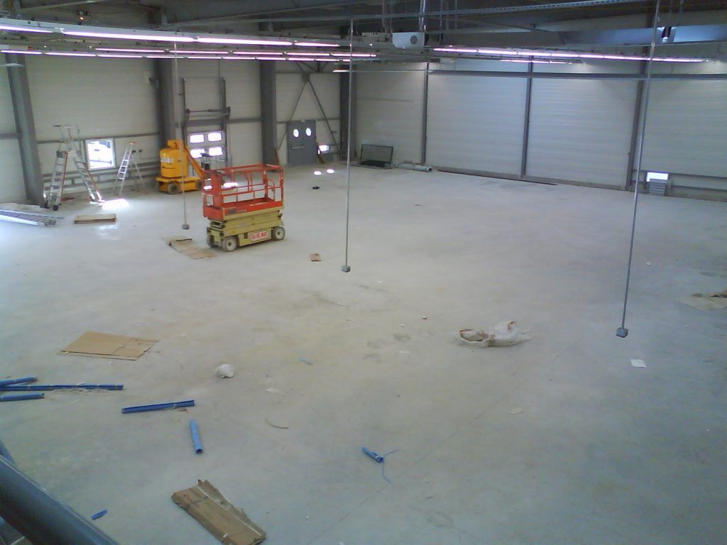 Vue du dessus d'un grand hangar industriel au sol recouvert de cartons et saletés