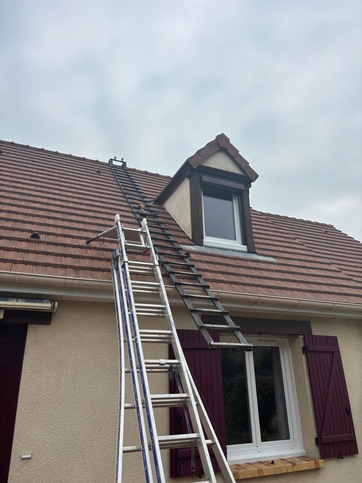 Échelle appuyée contre le toit d'une maison, près d'une lucarne, sous un ciel nuageux
