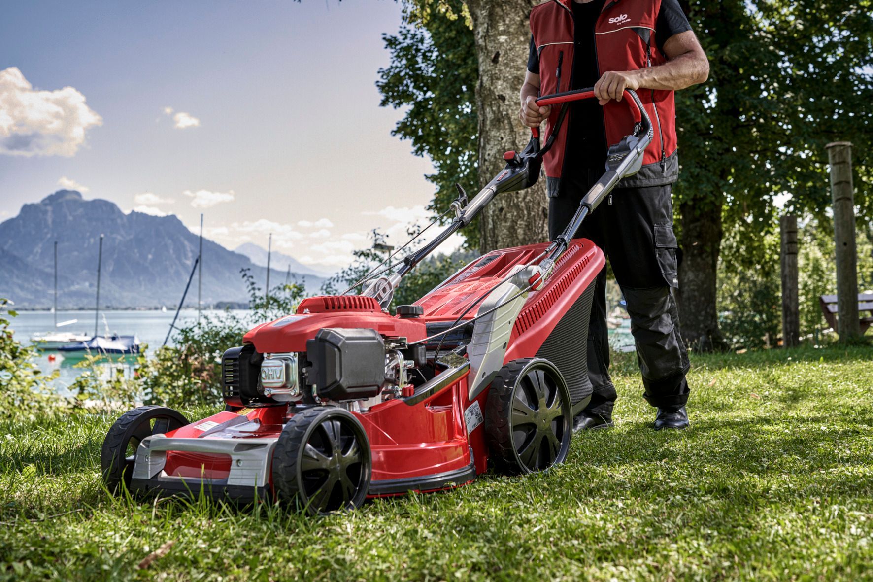 Ein Mann benutzt einen roten Rasenmäher auf einem üppigen grünen Rasen.