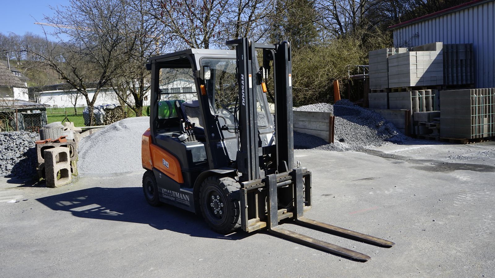 Ein Mann fährt einen Gabelstapler auf einem Parkplatz.