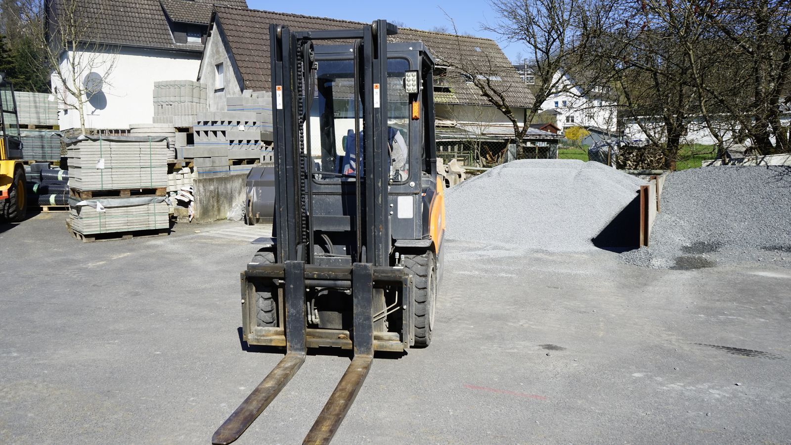 Ein Gabelstapler steht auf einem Schotterplatz