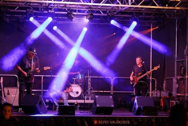 Foule floue lors d'un concert ou d'un événement illuminé par des lumières orange vif et des reflets au-dessus des têtes