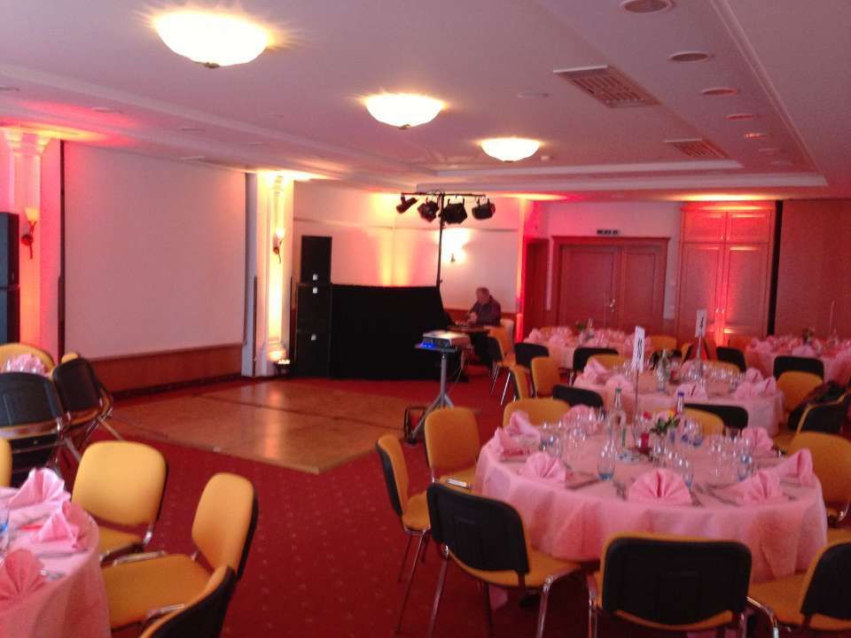 Salle de banquet avec tables rondes, moquette rouge et éclairage rose, aménagée pour un événement