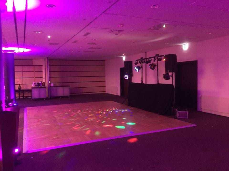 Salle de banquet vide avec éclairage violet, piste de danse et cabine de DJ avec haut-parleurs