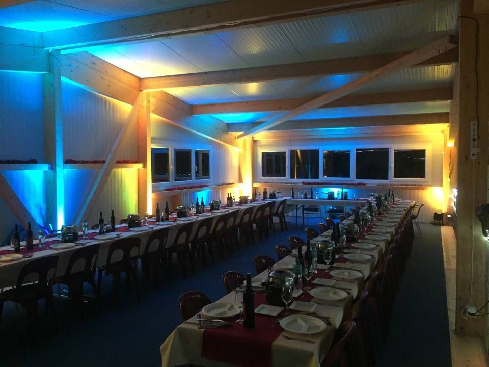 Salle de banquet faiblement éclairée, avec de longues tables éclairées à la bougie et une ambiance lumineuse bleu-or.