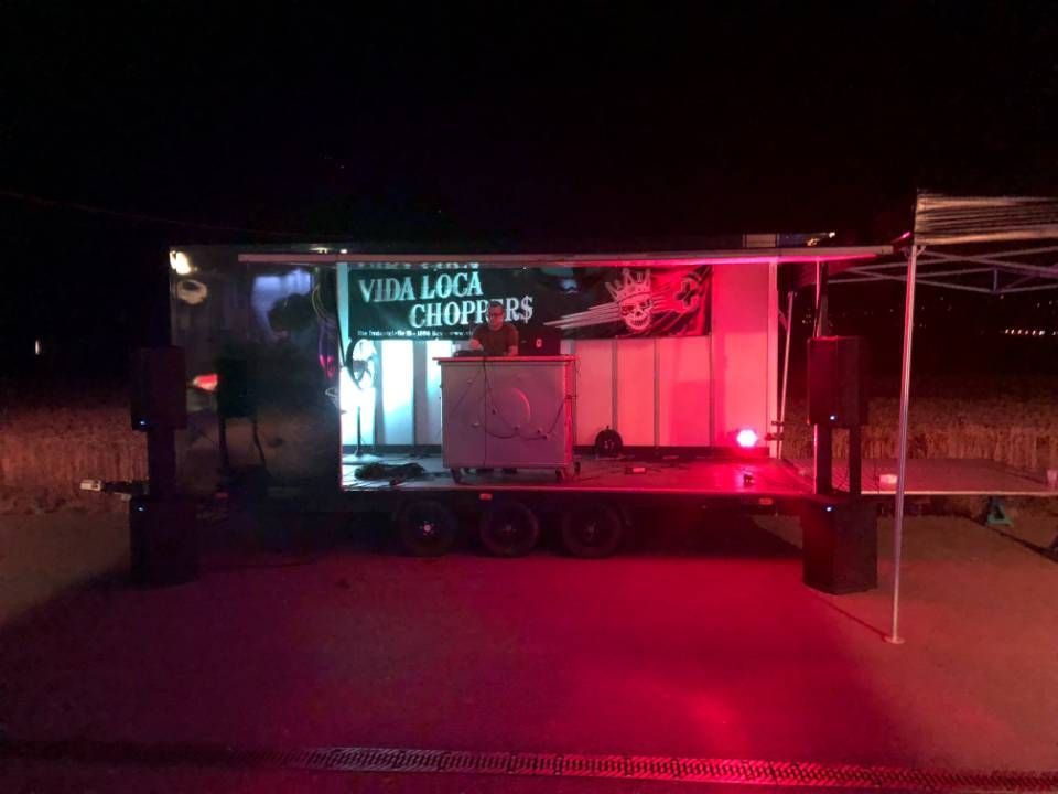 Un food truck illuminé en rouge la nuit, avec une pancarte indiquant « Viva La Chops » et un guichet de service ouvert.