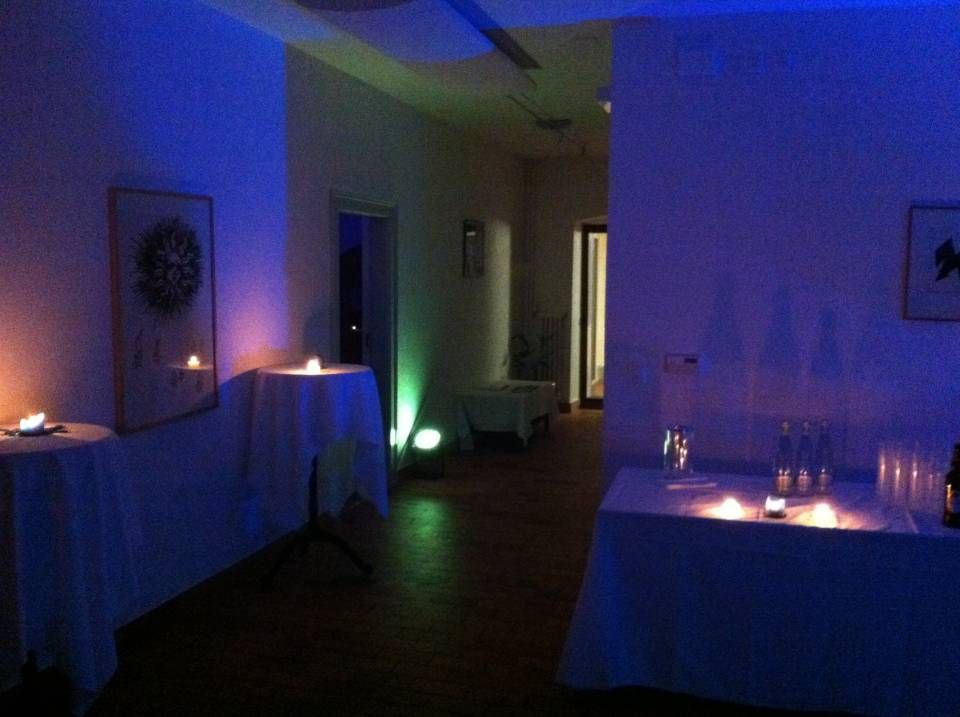 Salle de réception à l'éclairage tamisé, avec des lumières bleues et violettes, des tables nappées de blanc et des bougies qui brillent de part et d'autre.
