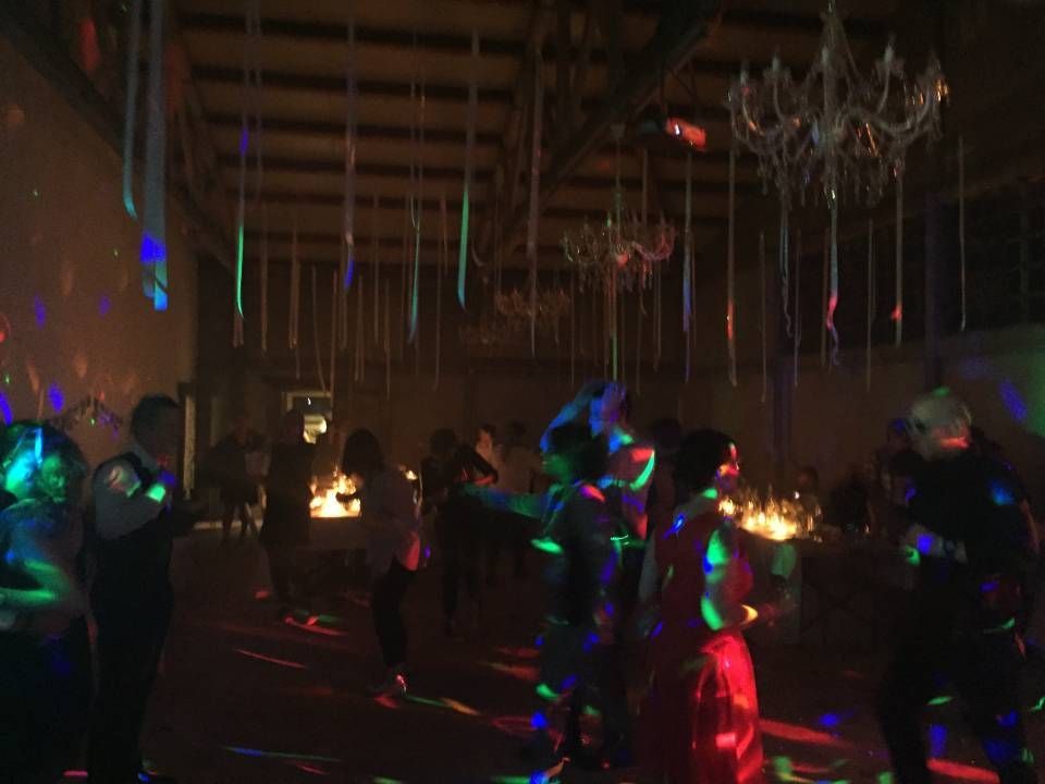 Des gens dansent dans une salle obscure illuminée par des lasers colorés et des lustres au-dessus de leurs têtes.