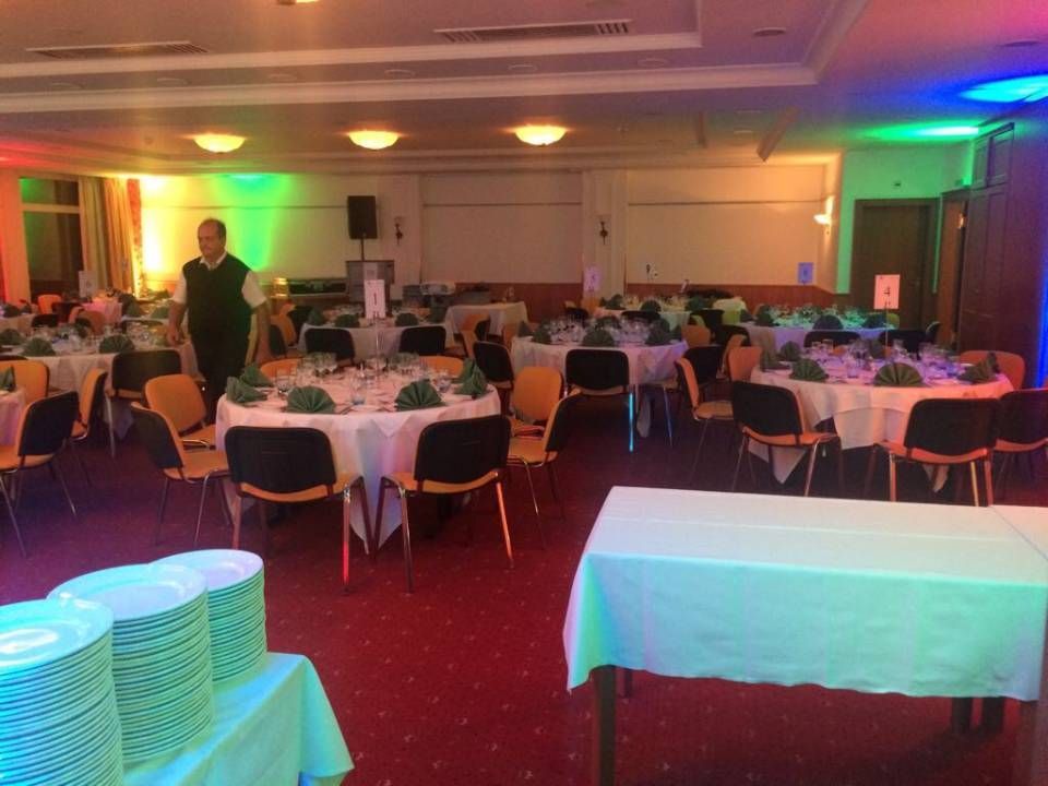 Salle de banquet avec tables rondes, tapis rouge et assiettes empilées au premier plan