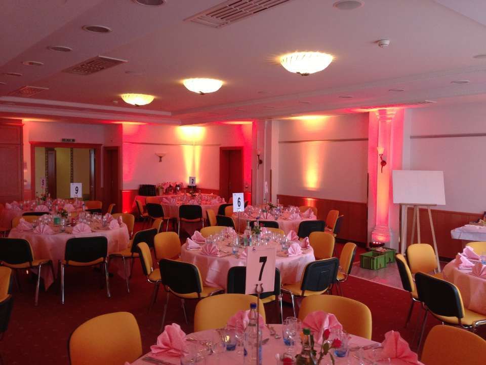 Salle de banquet avec tables rondes, chaises et éclairage rouge chaleureux, aménagée pour un événement