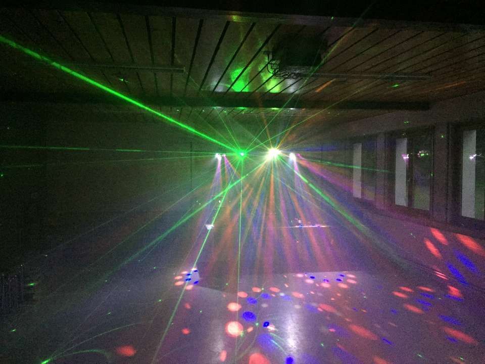 Pièce sombre avec des faisceaux laser verts et des spots lumineux disco colorés au sol et au plafond