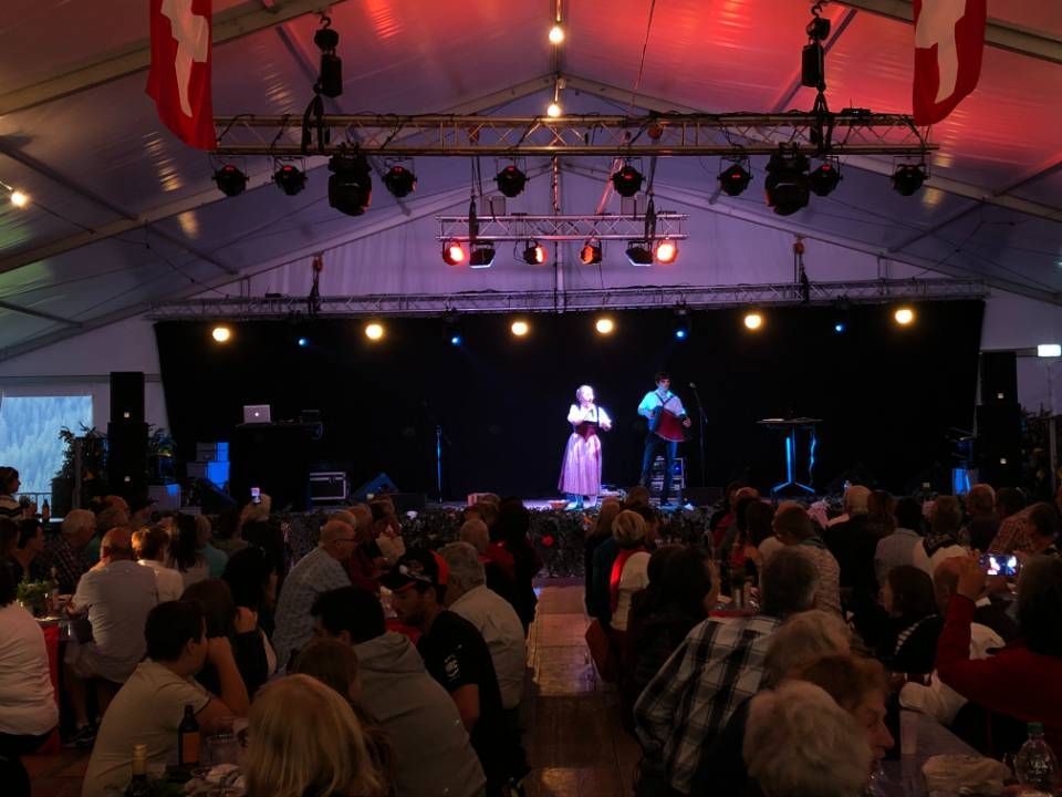 Concert en salle bondé sous un chapiteau, avec deux artistes sur une scène éclairée.