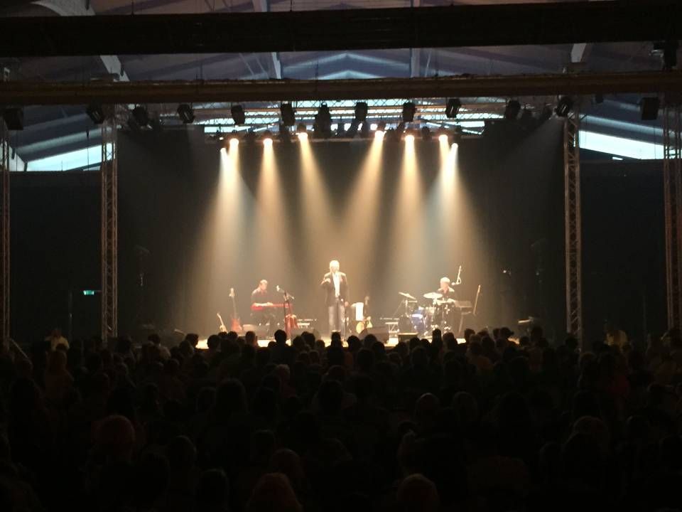 Scène de concert avec des projecteurs puissants et une foule en silhouette