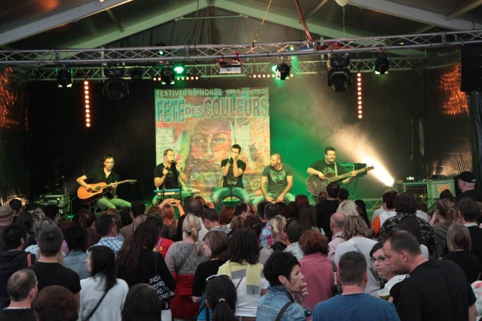 Scène de concert en plein air avec un groupe jouant sous des lumières vertes devant un public assis