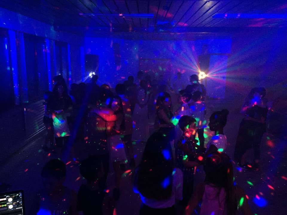 Des gens dansent dans une boîte de nuit plongée dans l'obscurité, éclairée par des lumières bleues et des points laser colorés.