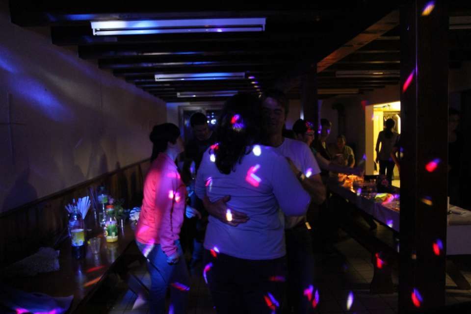 Des gens dansent dans une boîte de nuit tamisée, éclairée par des lumières disco colorées.