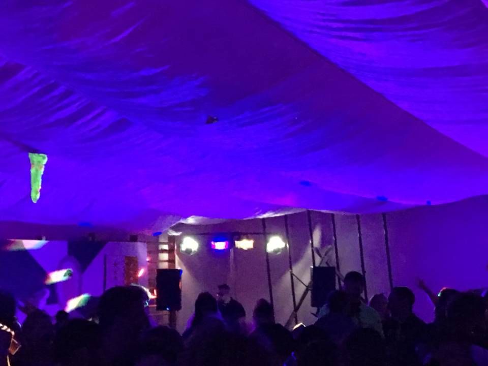 Foule sous une tente éclairée en violet lors d'un événement nocturne