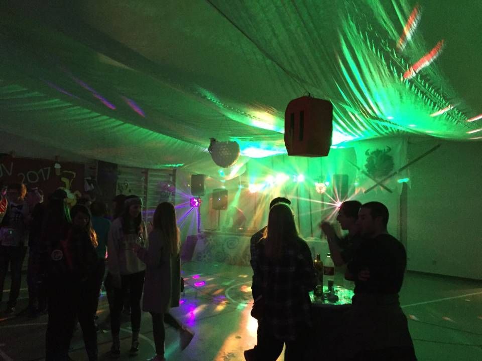 Des personnes dansent sous des lumières laser vertes dans une salle de fête intérieure faiblement éclairée