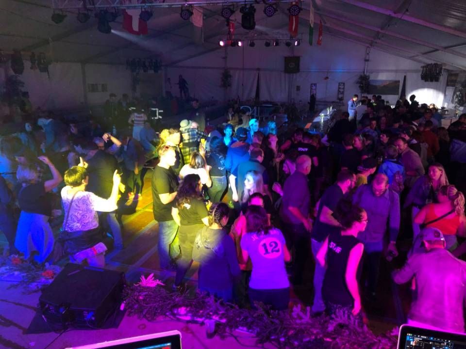 Piste de danse bondée sous des lumières colorées violettes, bleues et jaunes dans une grande salle