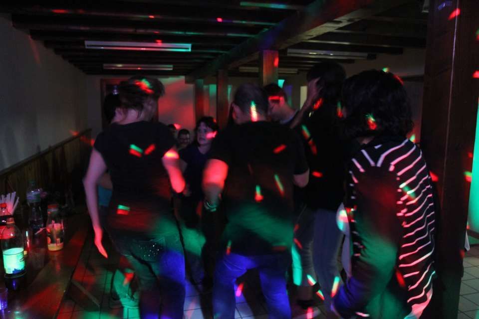 Des gens dansent dans un couloir sombre illuminé par des lumières rouges, vertes et bleues.